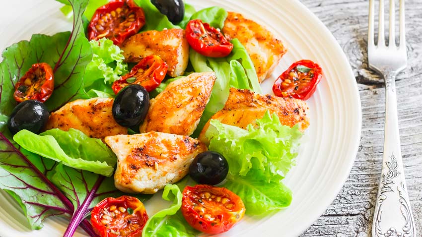salada com frango em um prato e um garfo ao lado - Alimentos para pessoas com colesterol alto